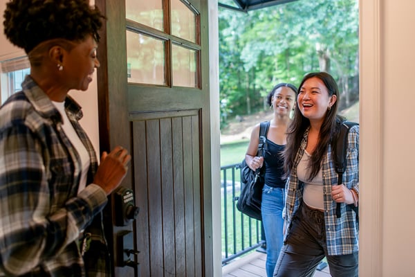 Host welcoming two guests at the front door of a home