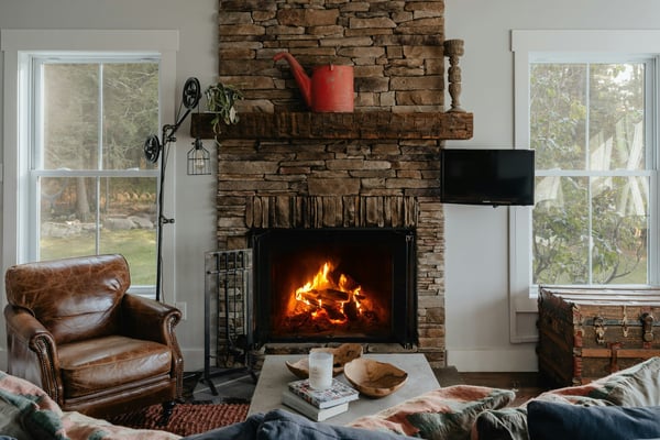 Stone fireplace living room with roaring fire and leather armchair