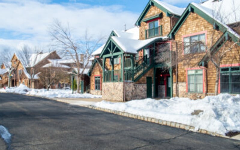 Stone and brick residential buildings with green trim and gabled roofs in snowy winter setting