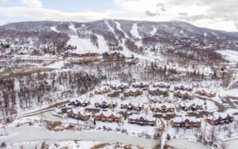 Aerial view of snowy mountain resort town with ski slopes and forested landscape
