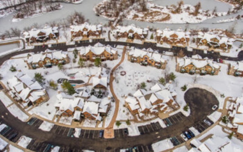 Aerial view of snowy suburban neighborhood with curved streets and residential homes