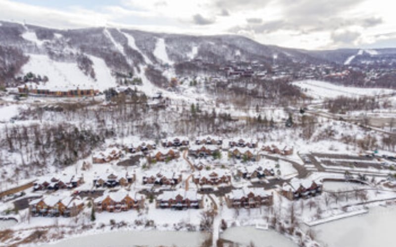 Aerial view of snowy mountain town with ski slopes and residential neighborhoods in winter