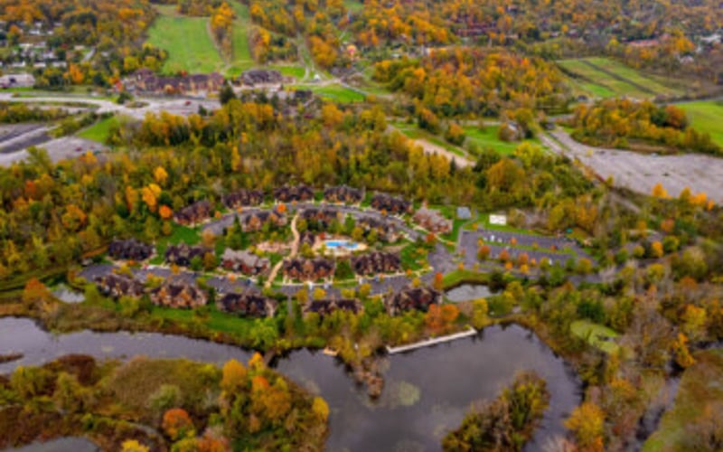 Aerial view of residential community surrounded by forested wetlands and winding waterways in autumn