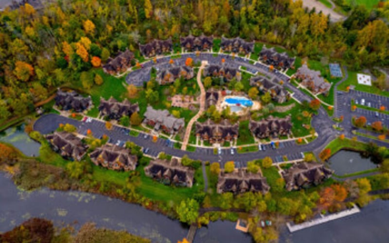 Aerial view of circular residential development with homes surrounding central green space and waterway