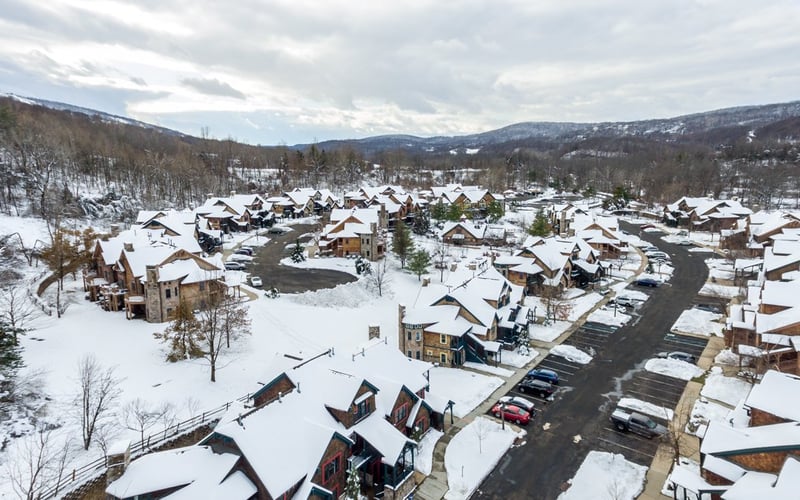 Aerial winter view of Condos at the Creek with snow-covered rooftops and forested hillside