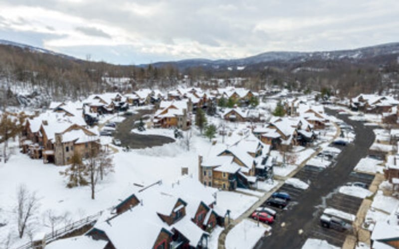 Snowy mountain town with residential buildings, cleared roads, and forested hills in background